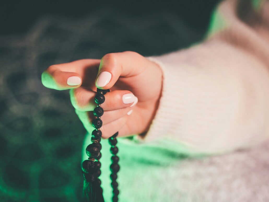 Woman holding mala beads in hand. Counting beads and reading mantra